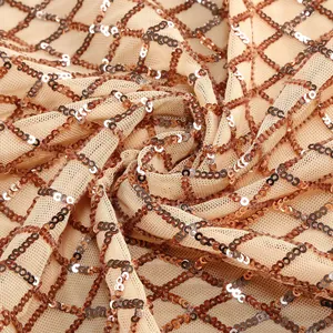 Dettaglio macro di tessuto a rete beige con paillettes oro rosa a motivo di rombi