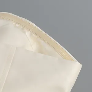 Gros plan sur la texture du tissu crème et les coutures fines d'une robe bustier élégante.