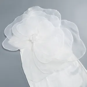 Close-up view of an elegant white dress with oversized layered organza flower detail