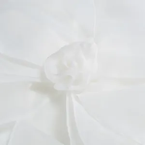 Detailed close-up view of elegant white sheer fabric floral decoration on party dress