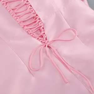 Gros plan détaillé de la robe en satin rose montrant le laçage style corset au dos.