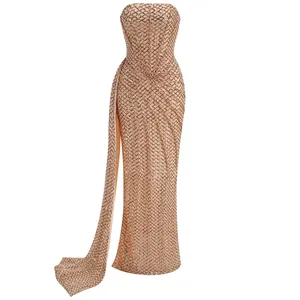 Elegante abito lungo senza spalline con paillettes champagne, spacco laterale e drappeggio.