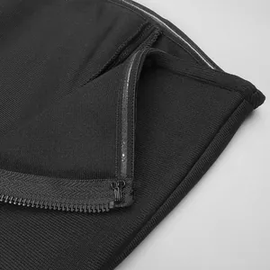 Close-up of black strapless dress featuring zipper detail and ribbed bandage fabric texture.