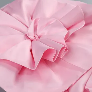 Gros plan de la grande fleur décorative en satin sur une robe fourreau rose bustier chic.