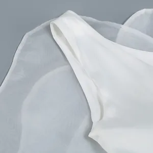 Close-up macro view of a white one-shoulder dress showing mesh and satin fabric textures