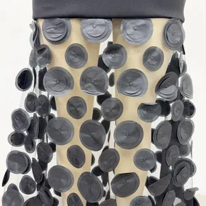 Detail view of black evening dress with 3D floral appliqués and sheer mesh stitching.