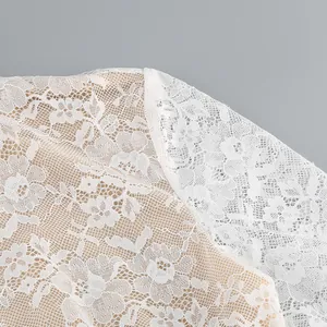 Macro view showing the intricate white floral lace jacquard texture and seam of this dress
