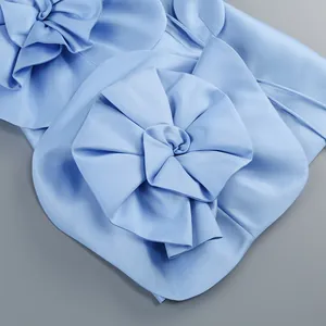 Vue détaillée de l'élégante fleur en tissu 3D sur une robe de soirée en satin bleu.