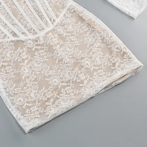 Detailed view of white lace jacquard fabric with structural fishbone accents on dress