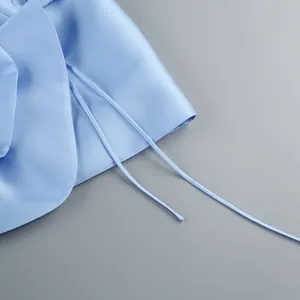 Détail d'une robe en satin bleu clair montrant le tissu lisse et les cordons fins