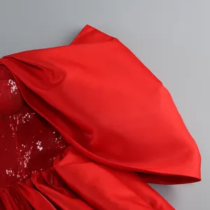 Dettaglio ravvicinato di raso rosso e paillettes su un abito da cocktail.