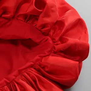 Primo piano del vibrante tessuto di raso rosso con eleganti dettagli di balze sull'orlo.