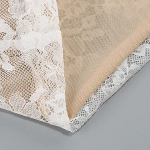 Macro view of delicate white floral lace fabric with nude lining on a stylish dress detail