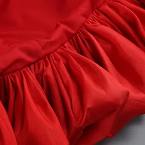 Dettaglio macro dell'elegante orlo a balze e del lucido tessuto di raso rosso di questo abito