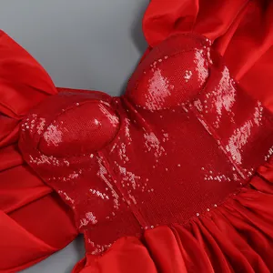 Dettaglio ravvicinato di un corpetto rosso di paillettes e gonna in raso di un abito rosso