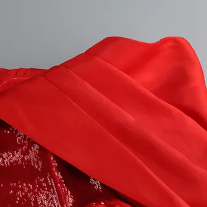 Dettaglio macro del tessuto in raso rosso e paillettes scintillanti sull'abito