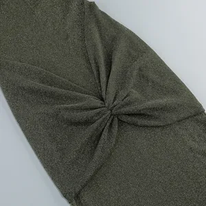 Close-up of twist knot detail on shimmering olive green metallic fabric dress