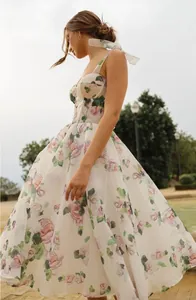 Side view detail of elegant floral midi dress with translucent white shoulder tie straps.