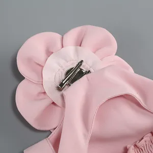 Detail of pink fabric flower accessory with silver alligator clip for women's clothing.