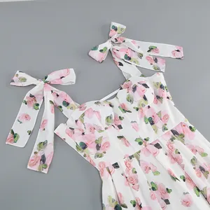 Detail of white midi dress with pink floral print and elegant shoulder tie bows.