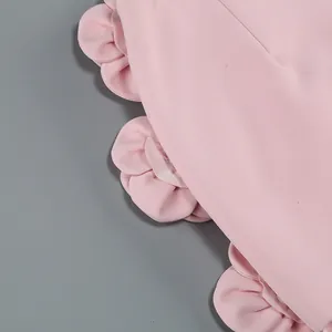 Close-up view of delicate pink ruffled flower embellishment on elegant two-piece garment