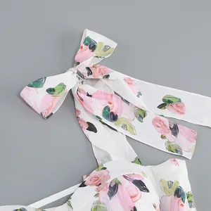 Detail view of floral print dress with elegant shoulder tie bow on grey background