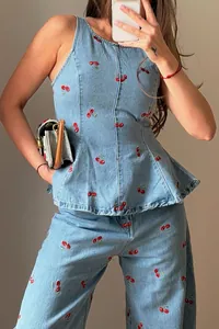 Close-up detail of retro light blue denim set with vibrant red cherry embroidery