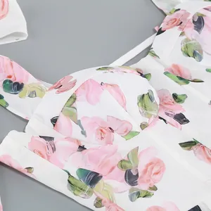 Close-up detail of a white slip dress with elegant pink rose floral patterns and corset seams.