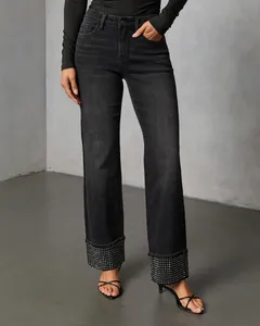 Detailed view of washed black straight-leg jeans with rhinestone embellished cuffs.
