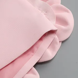 Macro detail of pink fabric set showing decorative flower petal ruffles and texture.