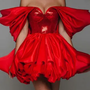 Abito a corsetto rosso con paillettes e voluminose maniche scoperte sulle spalle.