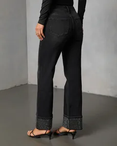 Detailed view of black straight-leg jeans featuring sparkling rhinestone-embellished cuffs