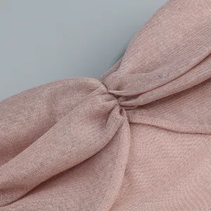 Close-up of shimmering pink mesh fabric with an elegant knotted detail on a slim-fit dress.