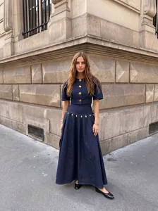 Κομψό σετ denim δύο τεμαχίων με χρυσά κουμπιά και μάξι φούστα σε δρόμο της πόλης