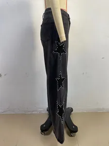 Close-up of wide-leg black jeans with star-shaped cutouts and decorative pearl bead trim.