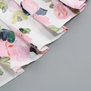Close-up detail showing the fine stitching and rose floral print hem of a white midi dress