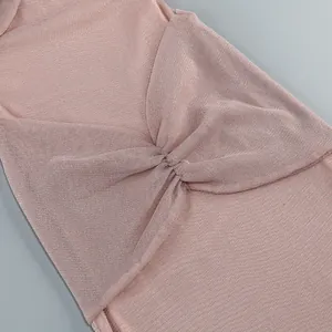 Close-up of the twist knot detail on a shimmering pink elegant maxi dress fabric.