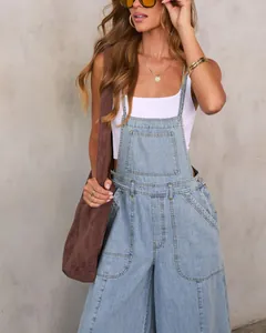 Detail view of light blue denim wide-leg overalls with large pockets and stylish bib straps