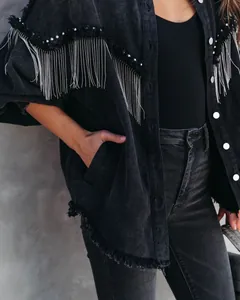 Close-up of black denim jacket featuring metallic chain fringe and silver rivet details