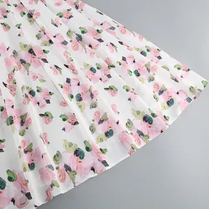 Close-up detail of the romantic pink rose floral print on a white flowy summer dress hem