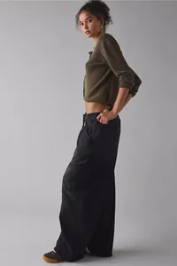 Side profile of a model wearing loose black cargo pants and a cropped olive green sweater.