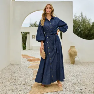 Full-length view of a women's long denim maxi dress with lantern sleeves in outdoor courtyard