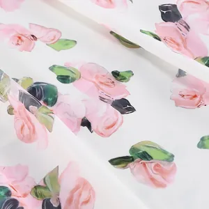 Close-up detail of romantic pink rose flower print on lightweight white dress fabric texture