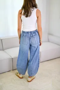 Back view of casual loose light blue balloon jeans for women in trendy street style.