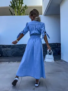 Back view of a stylish light blue long denim dress with puff sleeves and tie details.