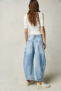 Back view of woman wearing loose light blue barrel-leg jeans with a white ribbed top