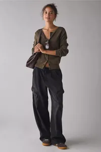 Women's stylish loose black cargo jeans paired with a green cardigan and brown bag