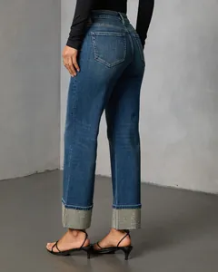 Detailed view of women's straight leg denim jeans featuring sparkling rhinestone cuffs