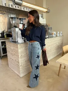 Lifestyle shot of women's wide leg jeans featuring large decorative star patches.