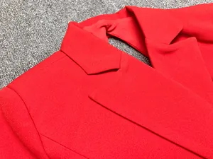 Gros plan d'un revers cranté rouge vif sur une robe blazer pour femme au tissu texturé